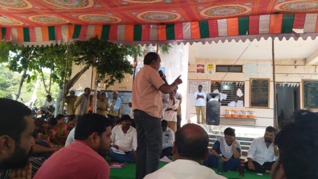 Speaker addressing people during a public meeting under a decorated tent